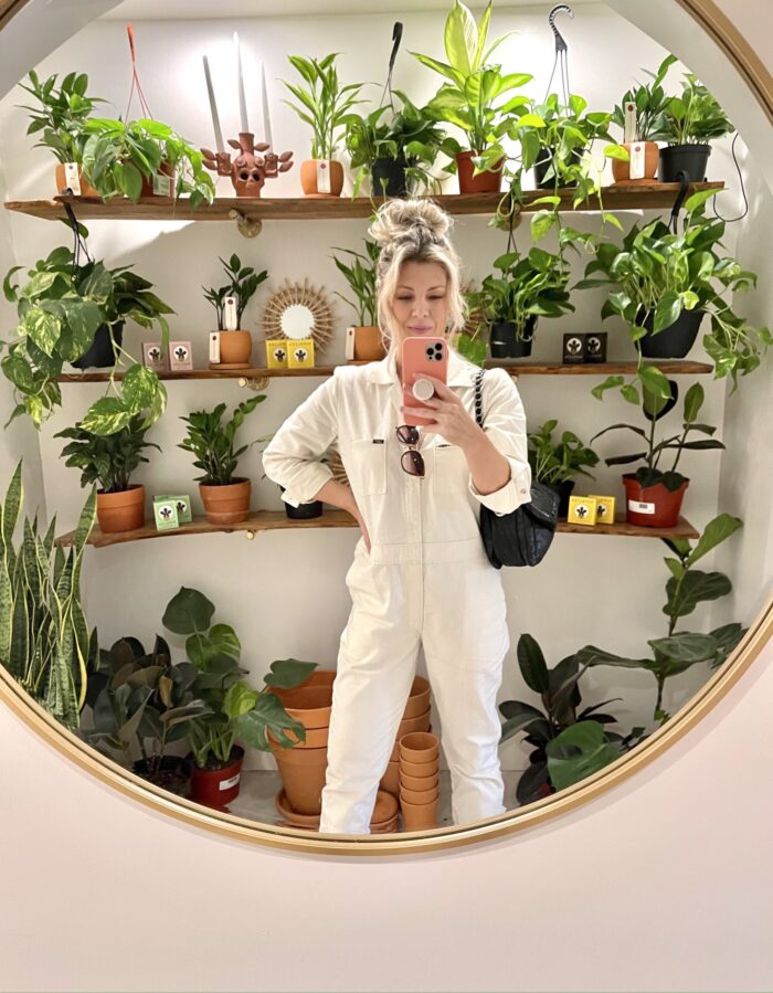 selfie in round mirror with plants in the background, ivory coveralls, lee unionalls, love maegan, blonde messy bun, lake arrowhead, shopping in lake arrowhead, bohemian village boutique