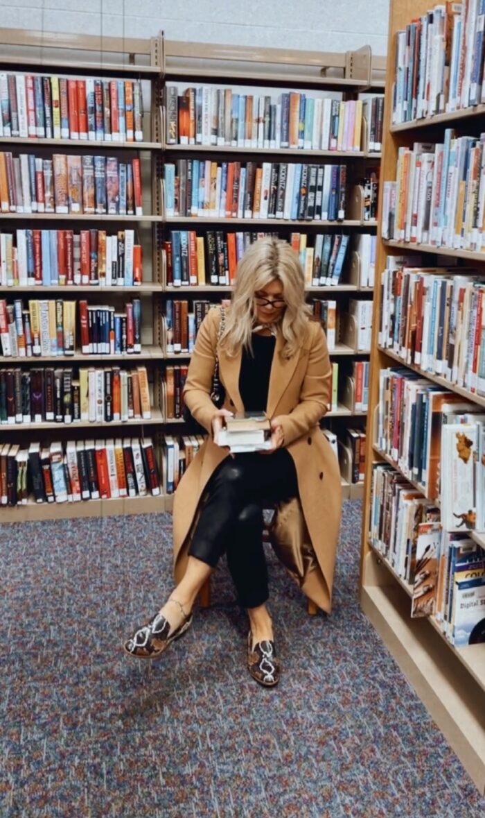 sitting in the library reading, camel coat with snakeskin loafers, black pants and sweter, camel coat, loafers, library aesthetic