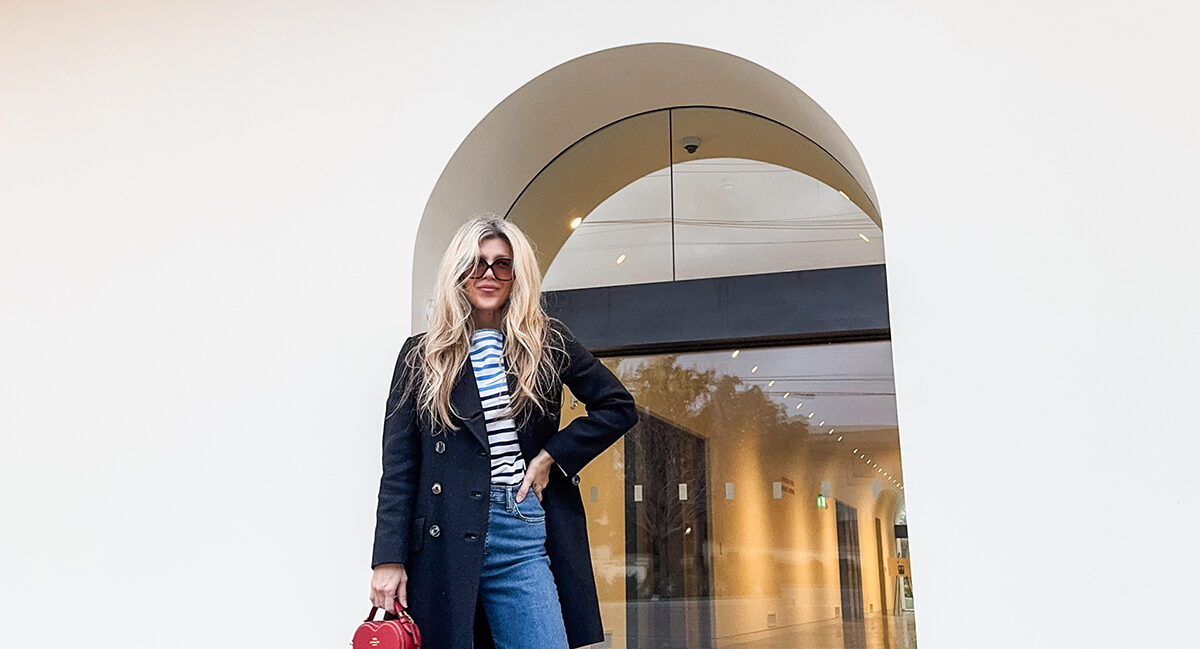 cloudy sky at dusk-spring style-wide leg jeans-white sneakers-striped top-military jacket-long blonde hair