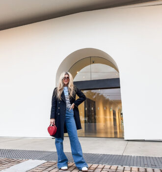 cloudy sky at dusk-spring style-wide leg jeans-white sneakers-striped top-military jacket-long blonde hair