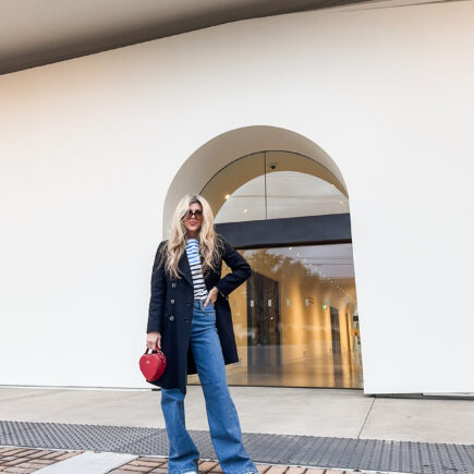 cloudy sky at dusk-spring style-wide leg jeans-white sneakers-striped top-military jacket-long blonde hair
