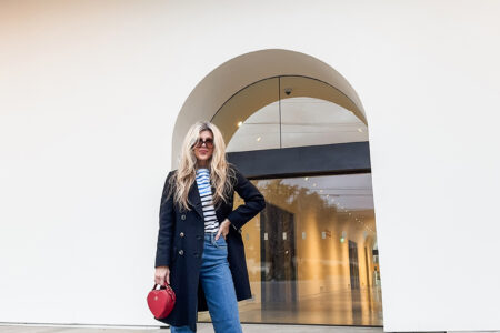 cloudy sky at dusk-spring style-wide leg jeans-white sneakers-striped top-military jacket-long blonde hair