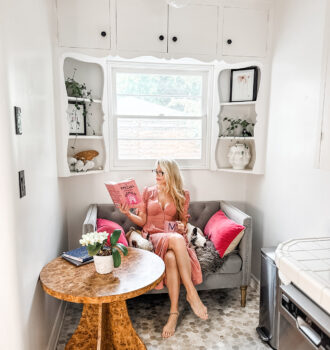 grey settee in a kitchen nook - pink dress - reading a book