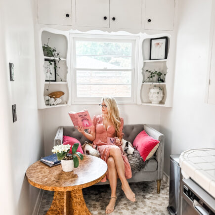 grey settee in a kitchen nook - pink dress - reading a book